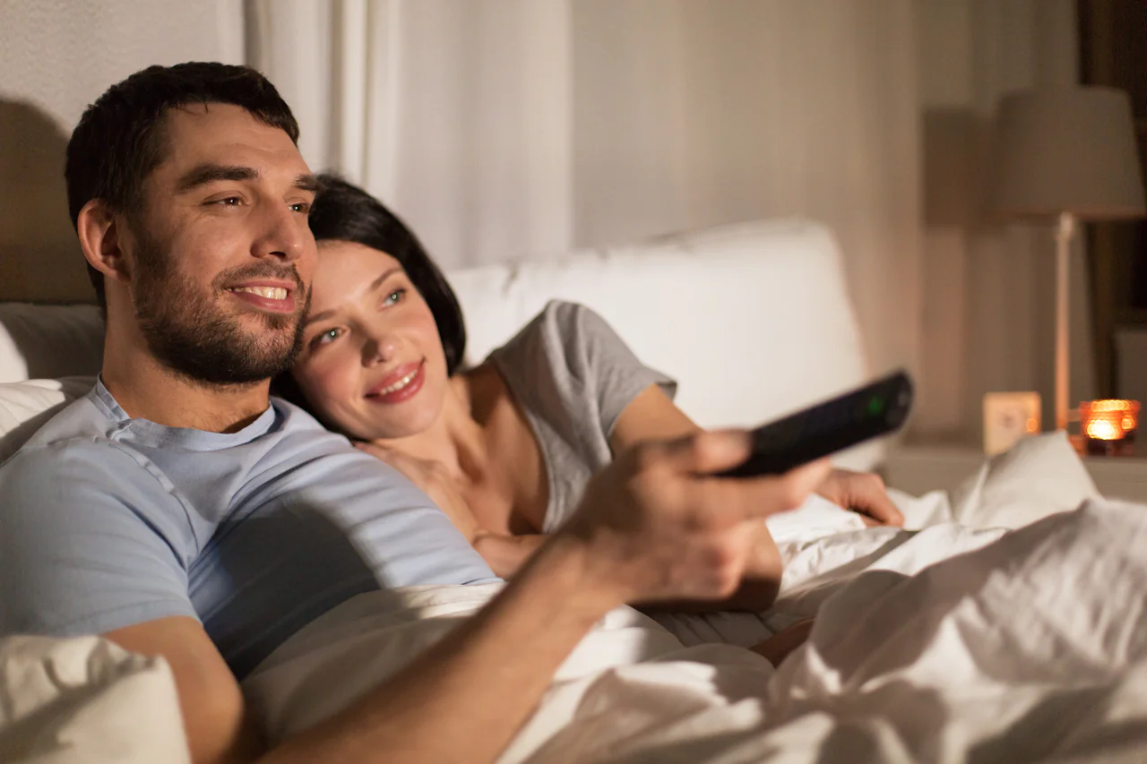 Man en vrouw in bed die tv kijken